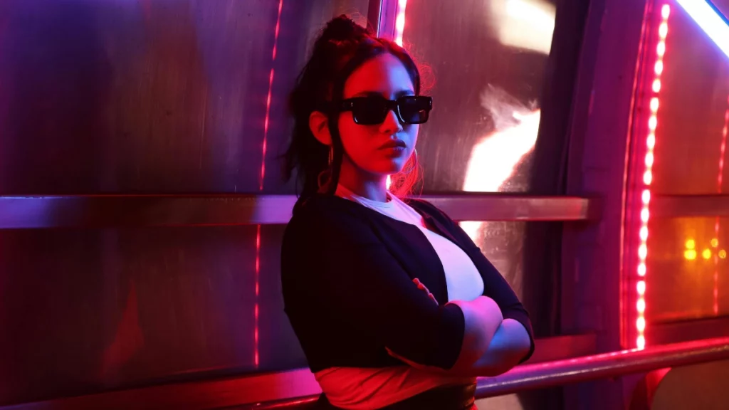 Mulher em ambiente iluminado por neon em tons de rosa e azul, representando o crescimento do mercado de games no Brasil e as novas oportunidades para mulheres na indústria.