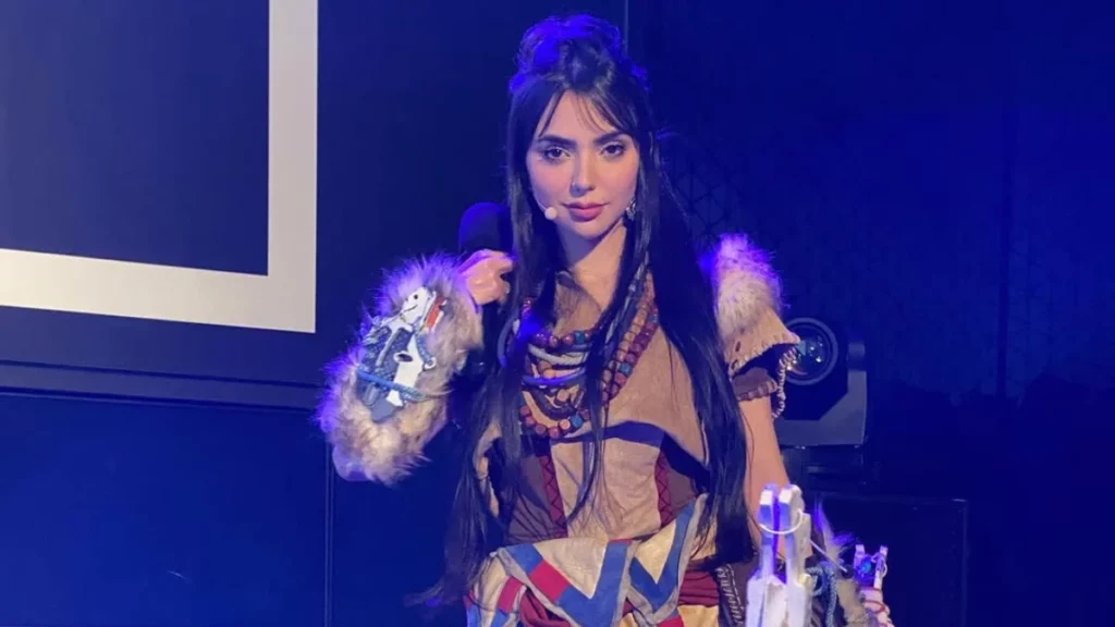 Mulher gamer em palco iluminado por luzes roxas representando liderança feminina no mercado de games