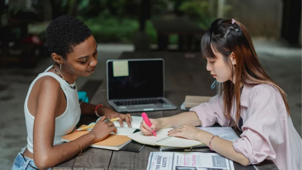 Mulheres colaboram em ambiente de estudo e planejamento, representando a preparação para montar um setup streamer iniciante e criar conteúdo online