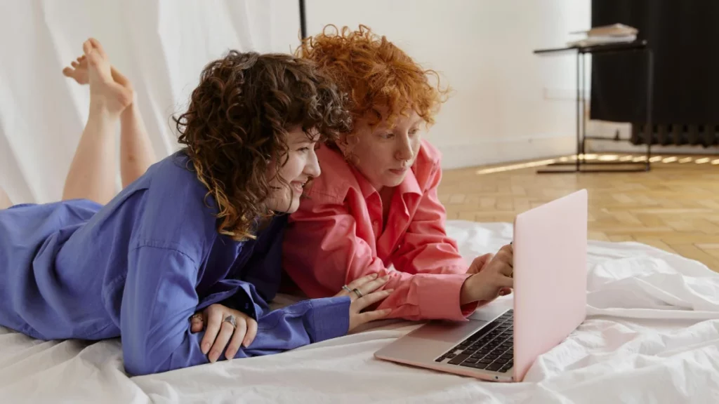 Duas mulheres analisam informações em um notebook enquanto estudam juntas, representando estratégias para subir rank no Valorant e evoluir no competitivo.