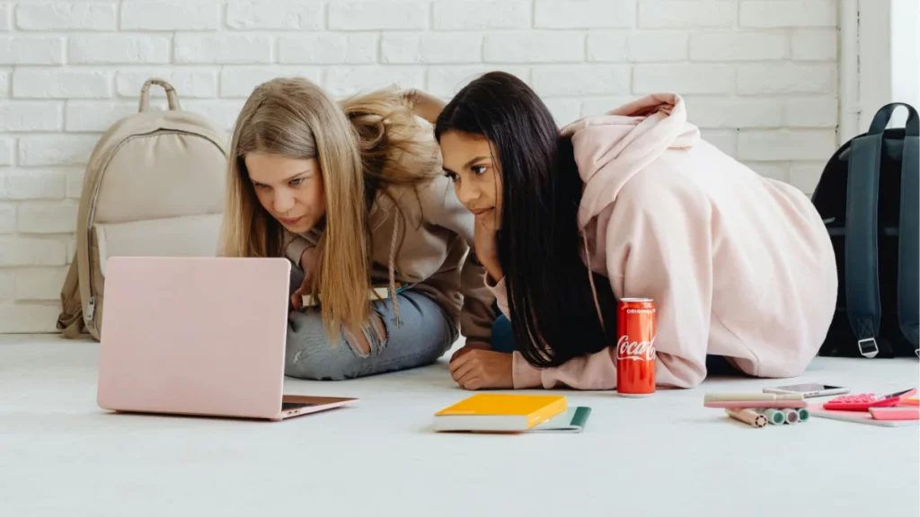 Duas jovens analisam conteúdo em notebook durante sessão de estudo e estratégia sobre melhores agentes Valorant.