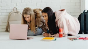 Duas jovens analisam conteúdo em notebook durante sessão de estudo e estratégia sobre melhores agentes Valorant.
